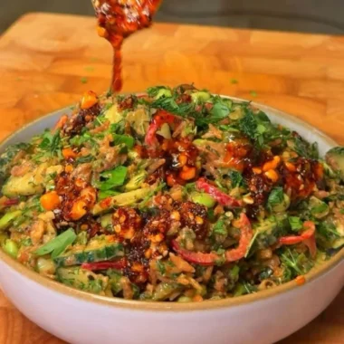 A vibrant bowl of Crispy Rice Salad with fresh vegetables and herbs.