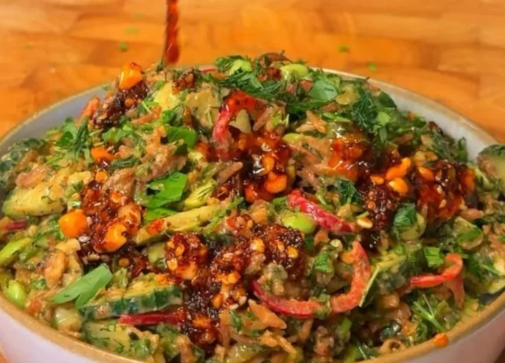 A vibrant bowl of Crispy Rice Salad with fresh vegetables and herbs.