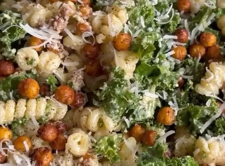 Kale Caesar Pasta Salad with croutons and dressing in a bowl