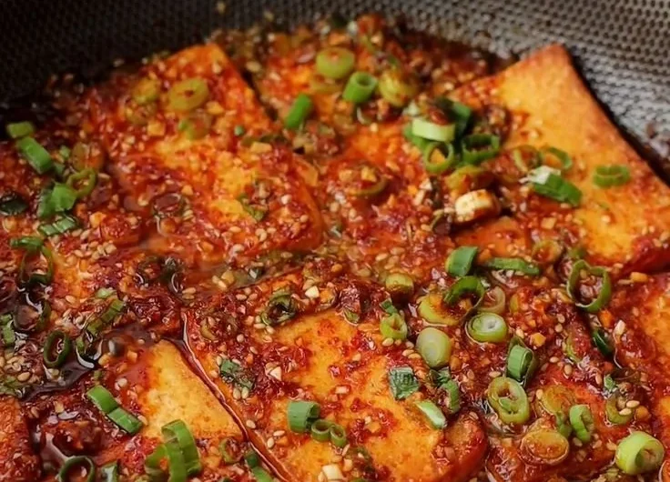 Plate of Korean Braised Tofu garnished with green onions and sesame seeds.