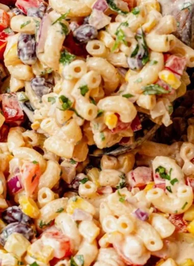 Bowl of vibrant Mexican macaroni salad with fresh vegetables and dressing.