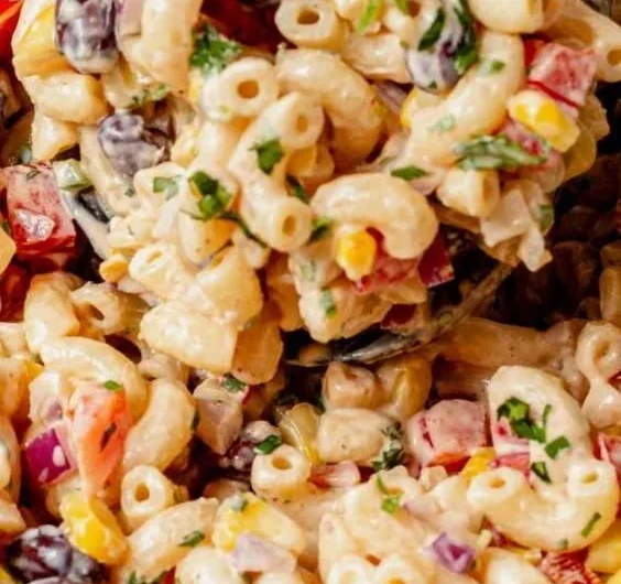 Bowl of vibrant Mexican macaroni salad with fresh vegetables and dressing.