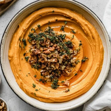 Pumpkin Whipped Feta Crostini garnished with herbs, served on a wooden platter.