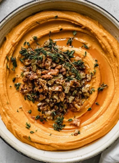 Pumpkin Whipped Feta Crostini garnished with herbs, served on a wooden platter.