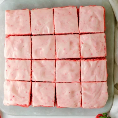 Delicious strawberry brownies with creamy frosting on a white plate