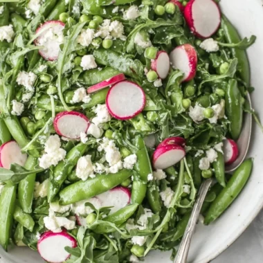 A colorful bowl of Sugar Snap Pea Salad with mixed veggies and dressing