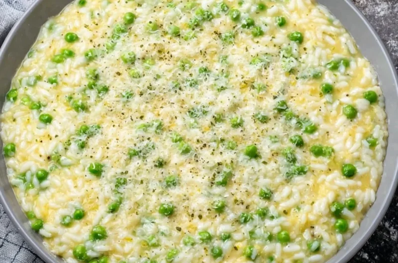 Bowl of warm and creamy rice and peas garnished with herbs
