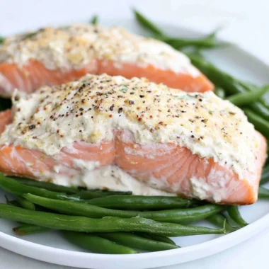 Baked salmon fillet topped with sour cream and mustard sauce on a plate