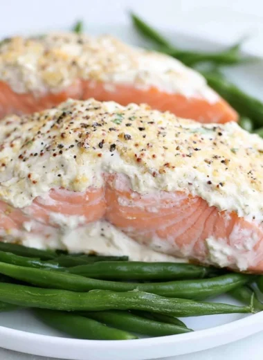 Baked salmon fillet topped with sour cream and mustard sauce on a plate