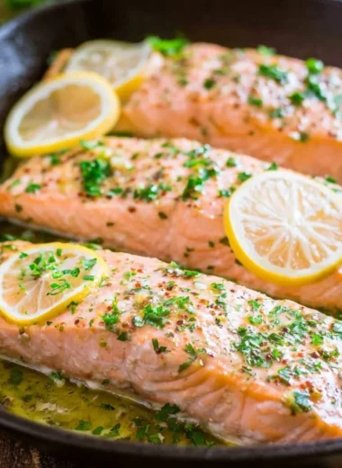 Delicious oven roasted salmon garnished with fresh herbs on a plate.
