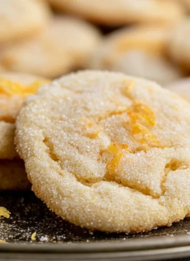 Soft and chewy lemon cookies on a plate with a lemon slice garnish.