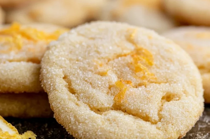 Soft and chewy lemon cookies on a plate with a lemon slice garnish.